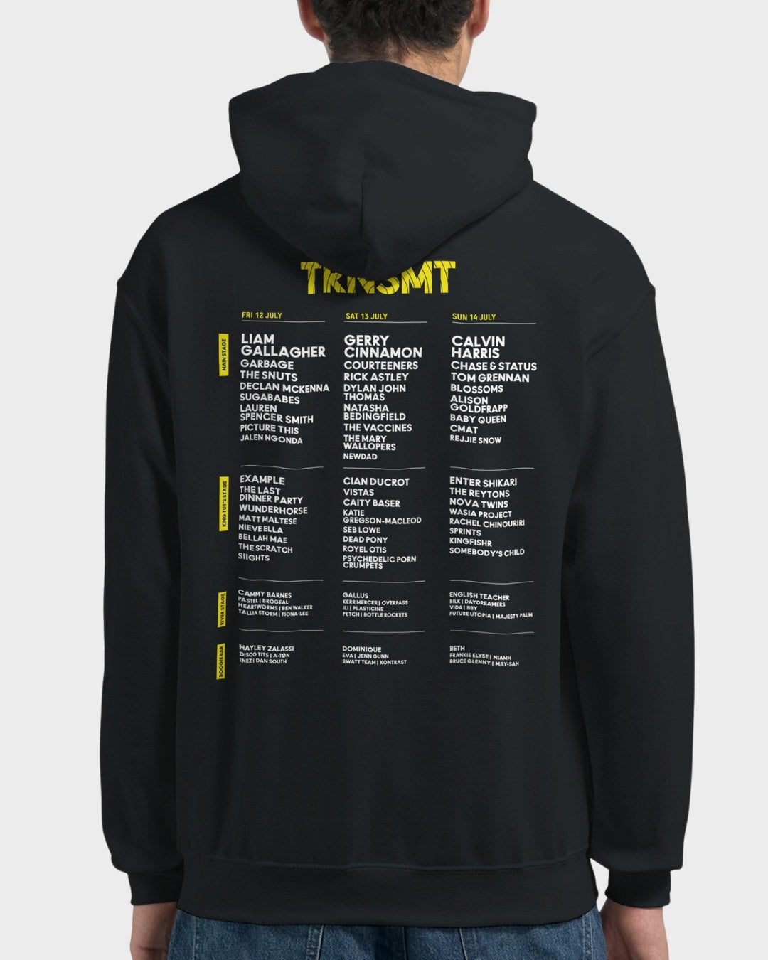 A person wears the TRNSMT Festival 2024 Line Up Black Pullover Hoodie featuring a music festival lineup in yellow and white text on the back, listing headliners like Liam Gallagher, Gerry Cinnamon, and Calvin Harris by date.