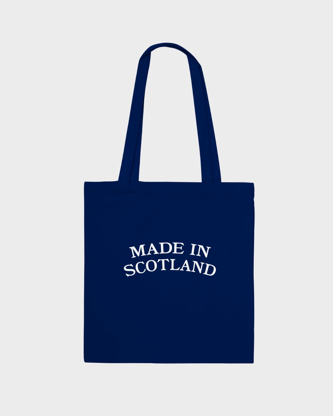 The TRNSMT Festival Made In Scotland Navy Tote Bag is a 100% cotton tote with two handles and "MADE IN SCOTLAND" in curved white text on the front, shown against a plain light gray background.